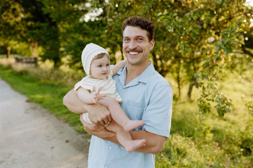 JT Seger holding one of his daughters outdoors